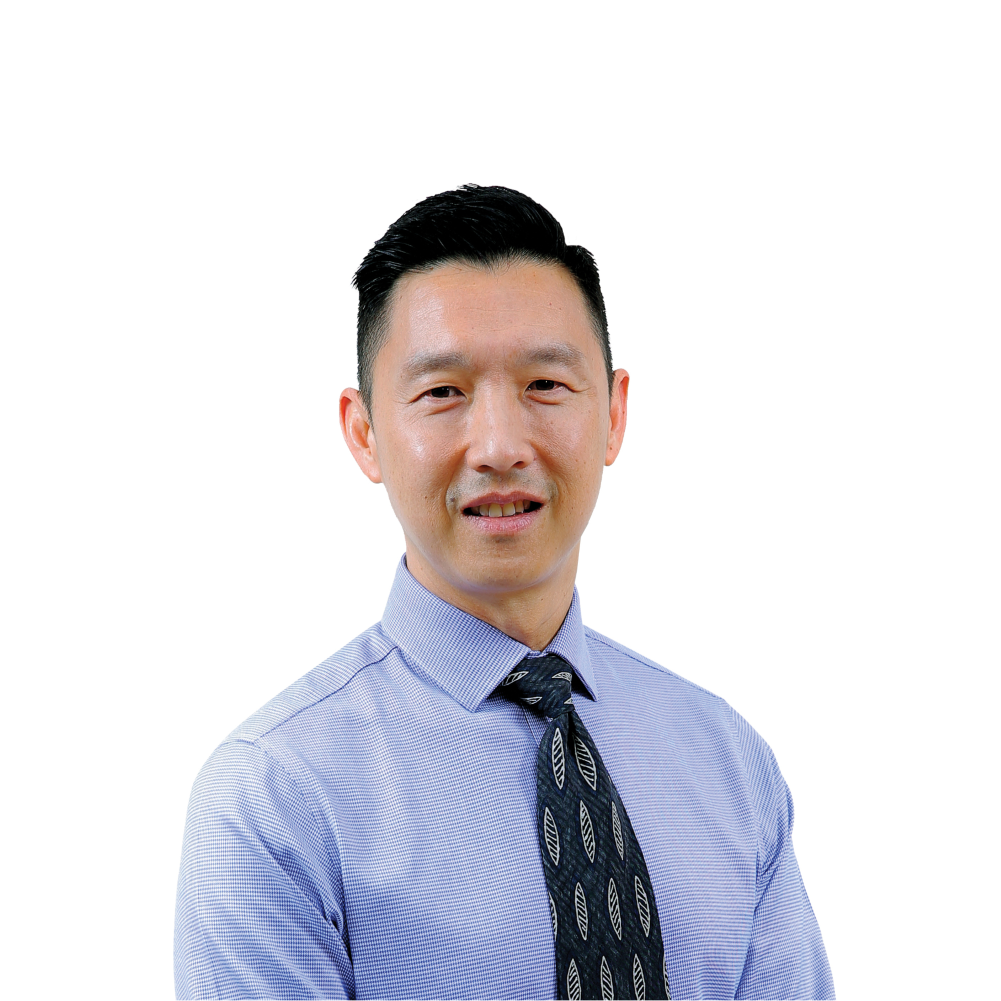 Asian man in a blue dress shirt and black tie, arms crossed at the wrist.